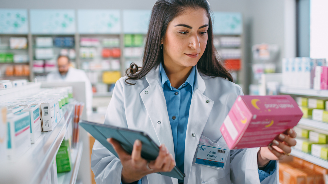 Apothekerin lächelt Medikament an